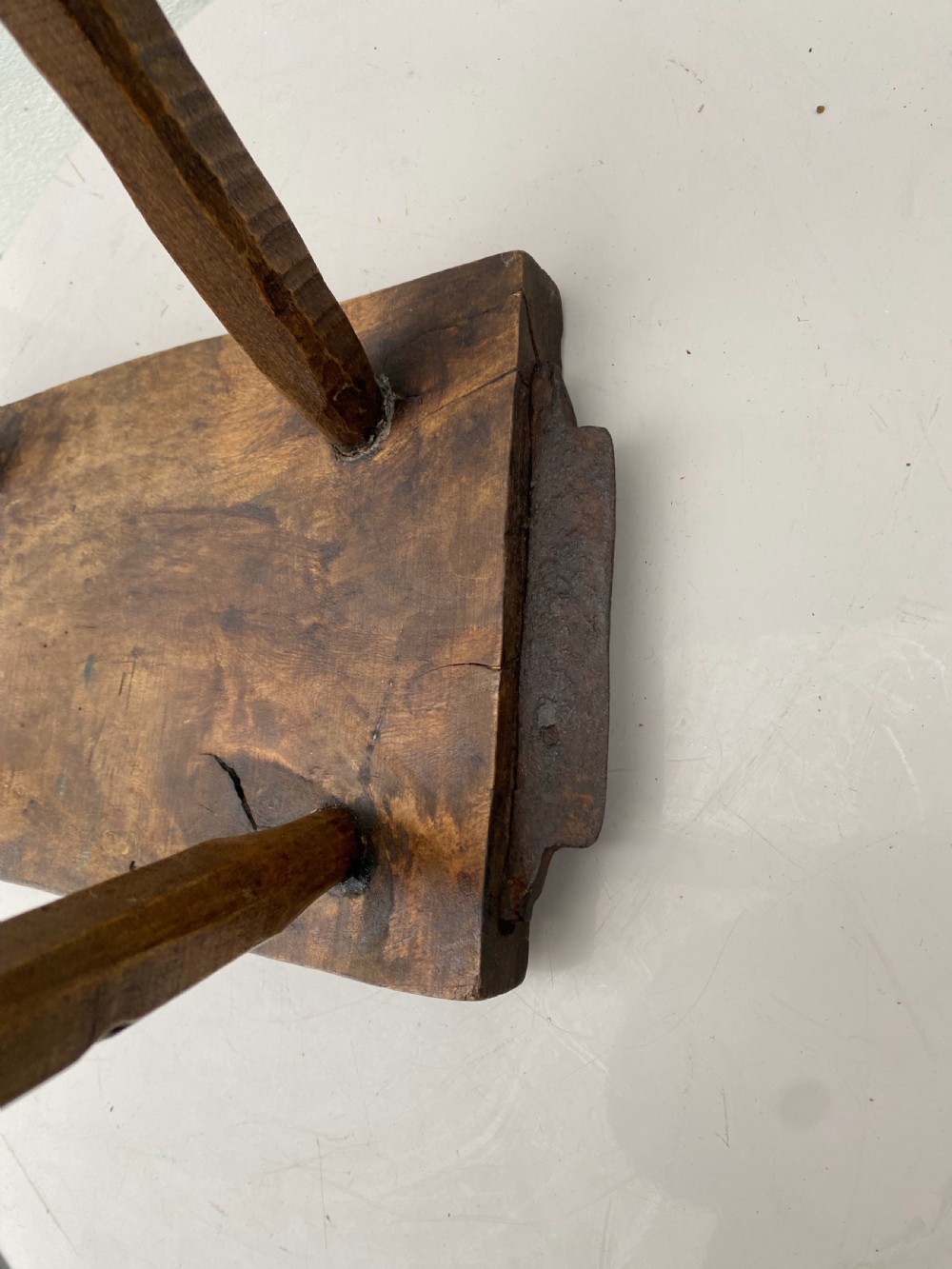 A rustic hand-carved rectangular wooden stool with four tapered legs wedged through a thick solid timber seat. View V
