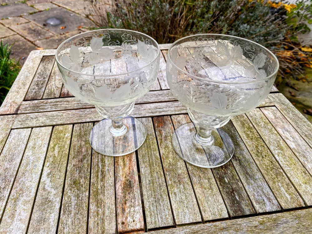 A pair of clear glass rummers decorated with etched grapevine motifs around the wide bowls and short stems. View II