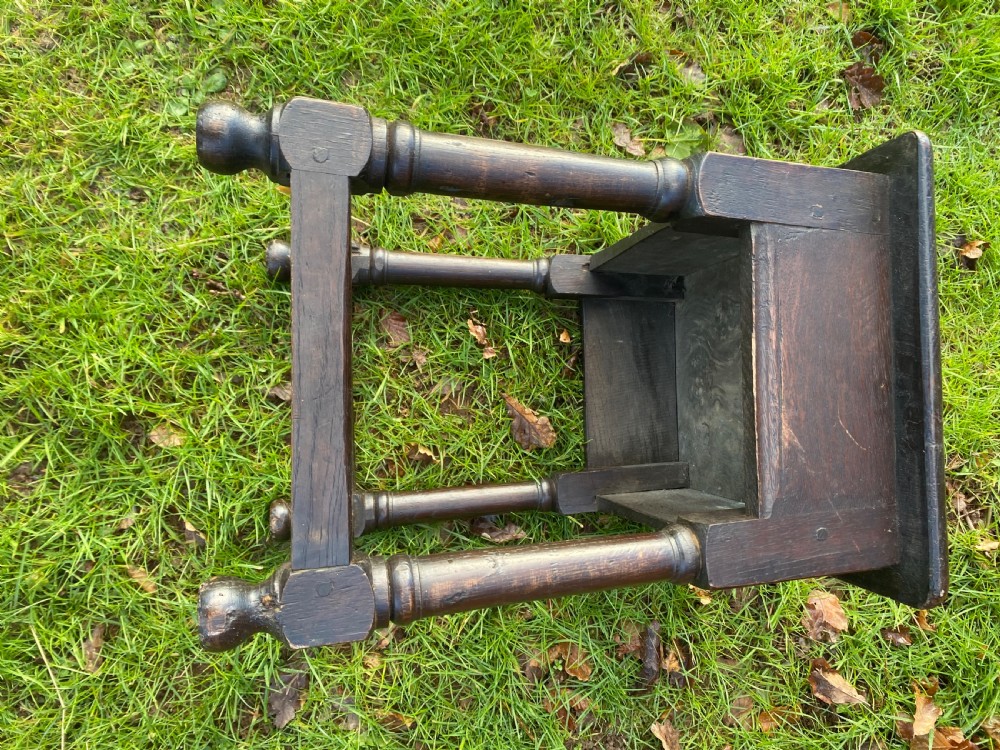 A dark oak joint stool featuring a rectangular top, rectangular frame apron, four turned legs, and low perimeter stretchers. View II