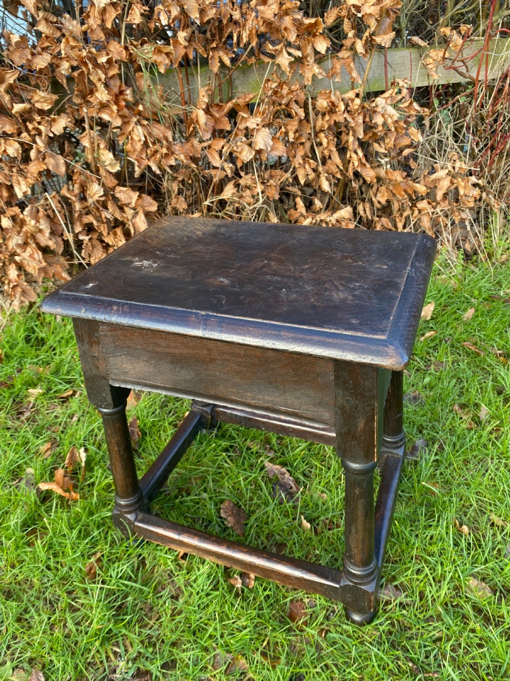 A dark oak joint stool featuring a rectangular top, rectangular frame apron, four turned legs, and low perimeter stretchers. View IV