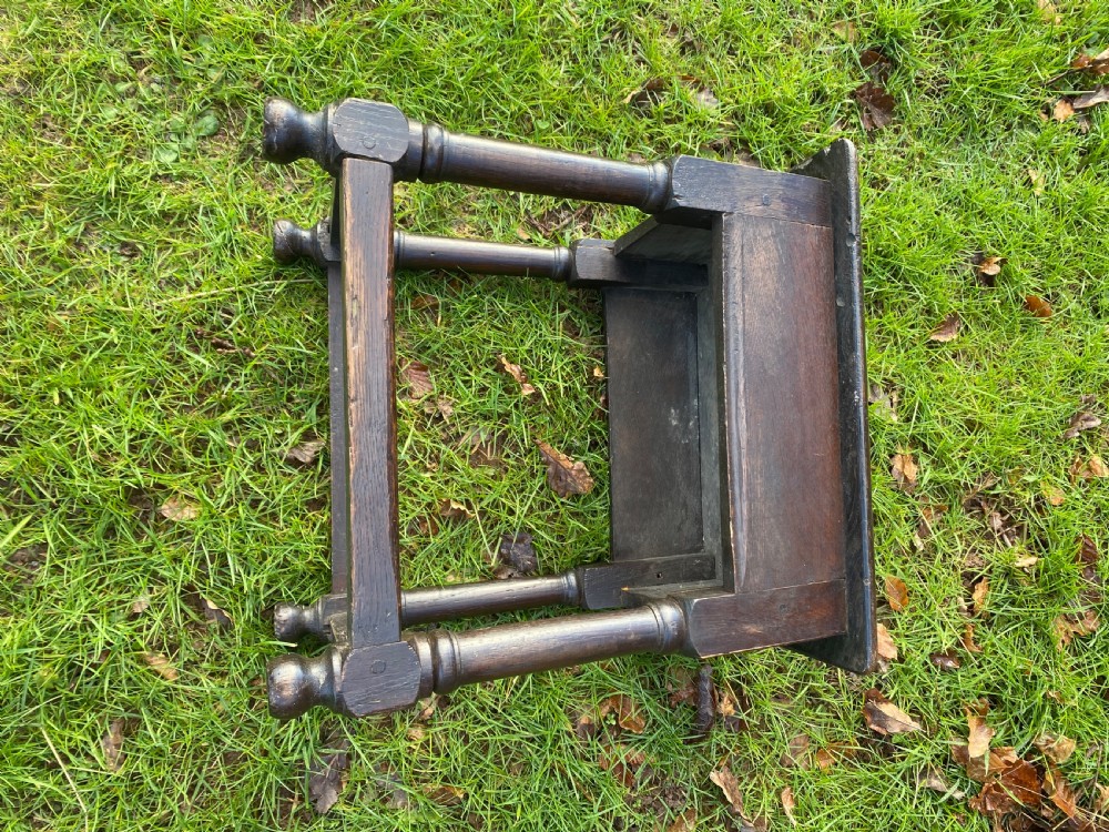 A dark oak joint stool featuring a rectangular top, rectangular frame apron, four turned legs, and low perimeter stretchers. View VII