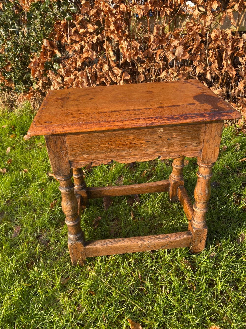 A solid oak joint stool featuring turned legs, lower perimeter stretchers, a shaped frieze apron, and a rectangular seat top. View IV