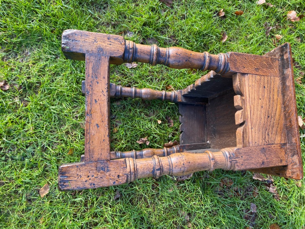 A solid oak joint stool featuring turned legs, lower perimeter stretchers, a shaped frieze apron, and a rectangular seat top. View VII