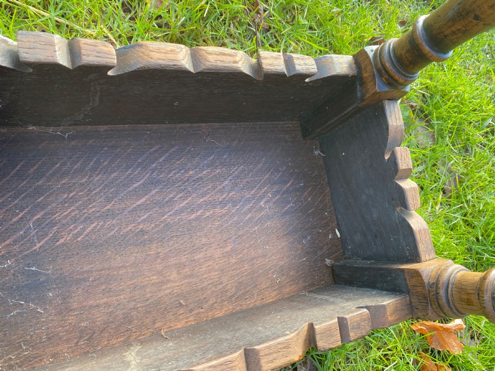 A solid oak joint stool featuring turned legs, lower perimeter stretchers, a shaped frieze apron, and a rectangular seat top. View X