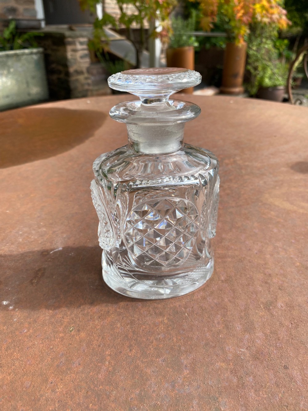 A clear 19th-century cut glass spirit decanter featuring diamond-patterned relief carvings and a fitted circular cut stopper.