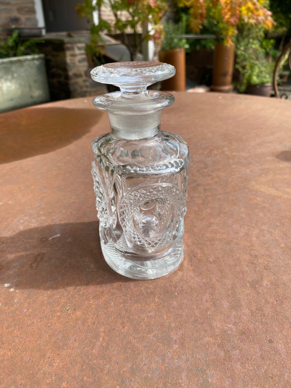 A clear 19th-century cut glass spirit decanter featuring diamond-patterned relief carvings and a fitted circular cut stopper. View II