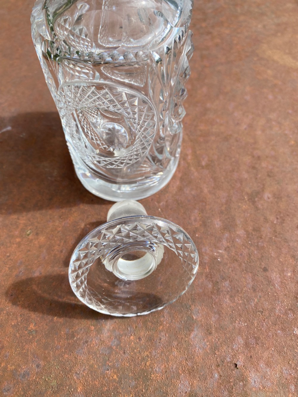 A clear 19th-century cut glass spirit decanter featuring diamond-patterned relief carvings and a fitted circular cut stopper. View V