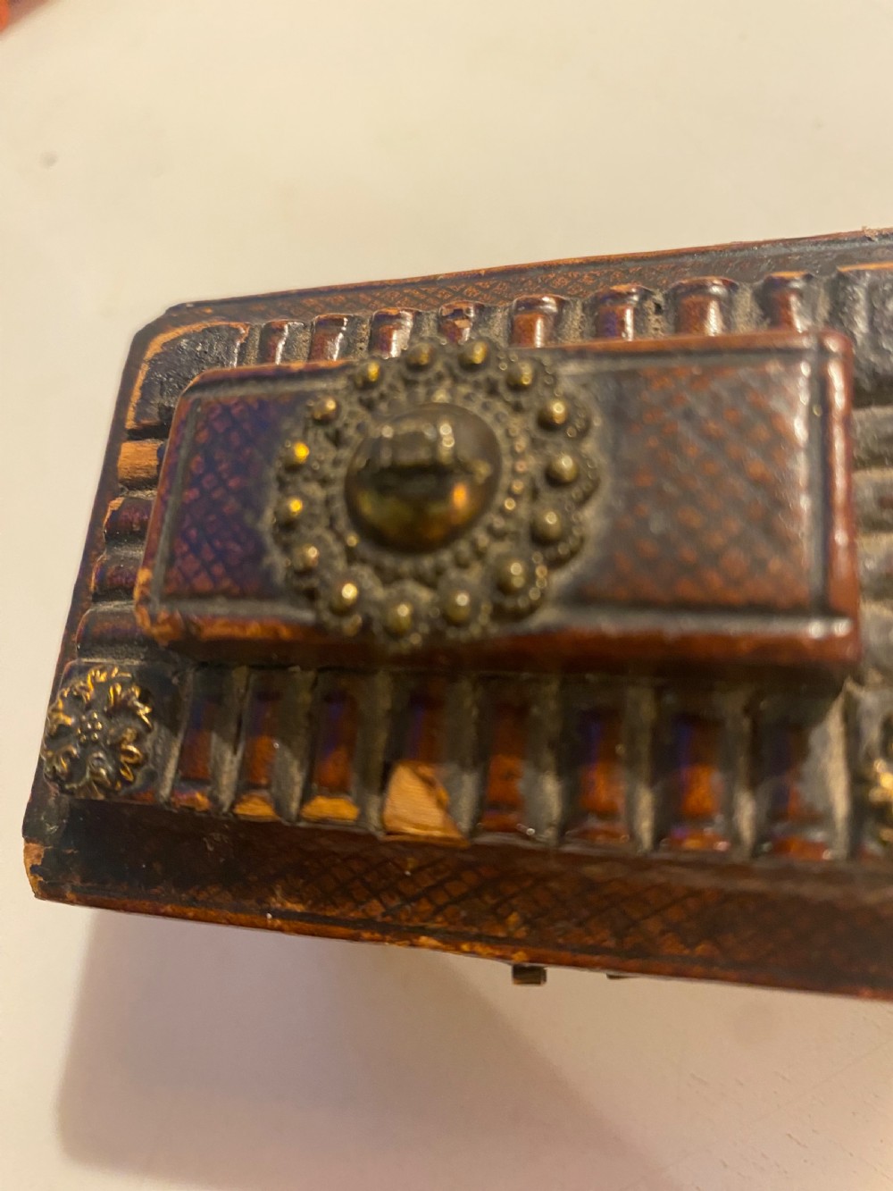 An antique dark brown tooled leather trinket box featuring a tiered lid with decorative brass mounts, brass hook clasp, and round ball feet. View IX