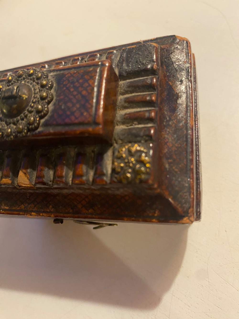 An antique dark brown tooled leather trinket box featuring a tiered lid with decorative brass mounts, brass hook clasp, and round ball feet. View X