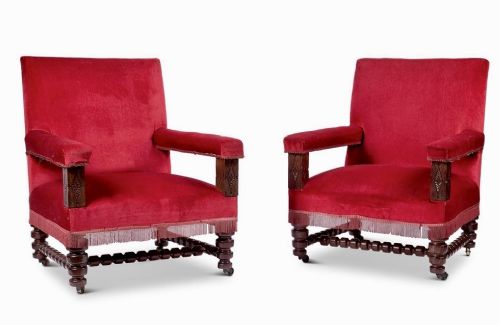 fig 1. A pair of oversized Victorian armchairs upholstered in crimson red velvet with fringe trim, featuring carved oak arm supports and bobbin-turned legs.