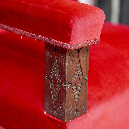 fig 4. A pair of oversized Victorian armchairs upholstered in crimson red velvet with fringe trim, featuring carved oak arm supports and bobbin-turned legs.