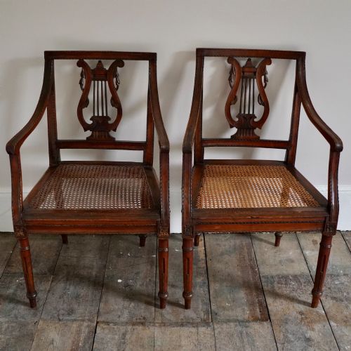 fig 1. A matching pair of 19th-century Regency style mahogany armchairs featuring carved lyre back splats and woven cane seats.