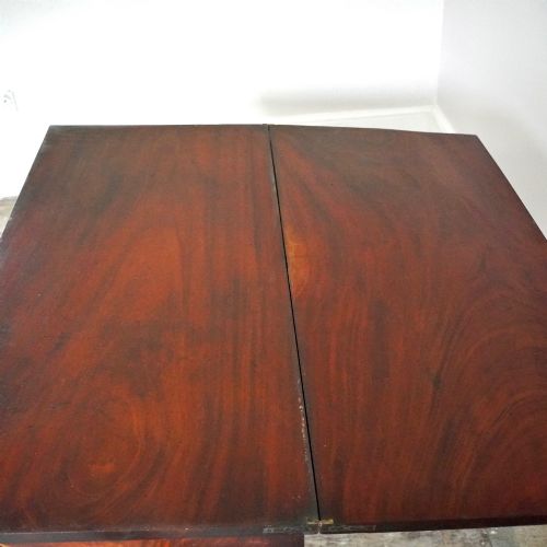 fig 9. A Victorian figured mahogany card table featuring a turnover top, carved frieze, turned pedestal, and scroll legs with castors.