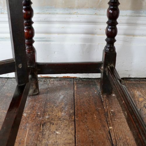 fig 7. A dark brown antique oak gateleg drop-leaf table with turned legs and an oval top.