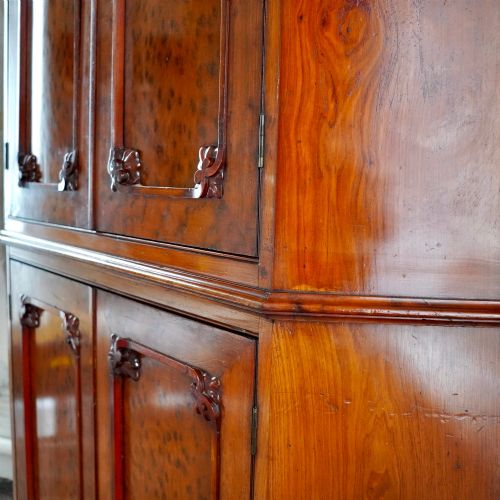 fig 4. A tall, two-tier William IV corner cupboard crafted from dark plum pudding mahogany, featuring panelled double doors on both top and bottom sections with carved detail and a pediment top.