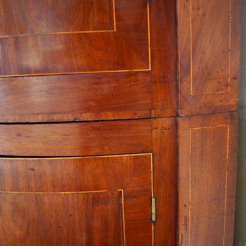 fig 8. A tall Georgian mahogany bowfront corner cupboard featuring two upper curved doors, two lower curved doors, and fine line inlay.