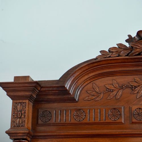 fig 2. A tall 19th-century Continental open wooden bookcase featuring an ornate carved pediment, fluted side columns, panelled back, and multiple adjustable shelves.