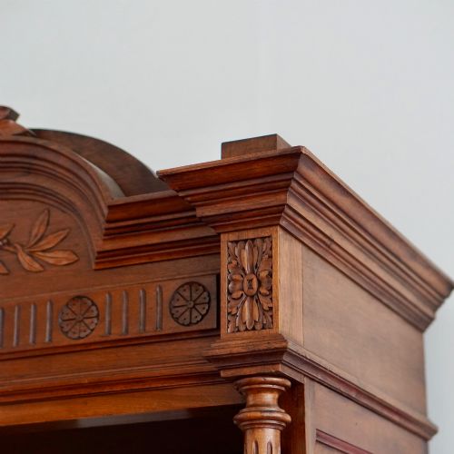 fig 3. A tall 19th-century Continental open wooden bookcase featuring an ornate carved pediment, fluted side columns, panelled back, and multiple adjustable shelves.