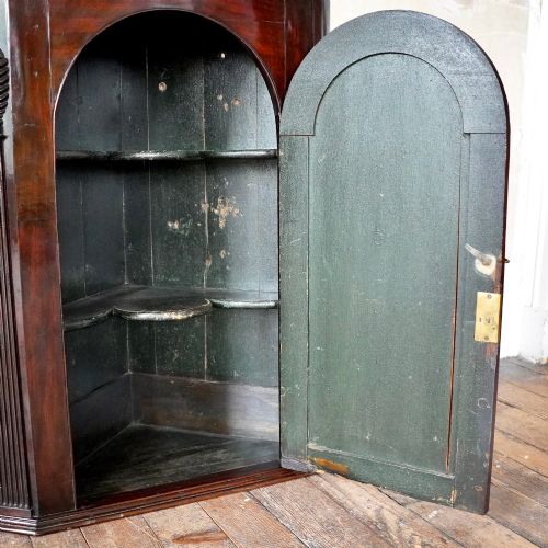 fig 3. Mid-18th century Georgian mahogany hanging corner cupboard featuring an arched panelled door, brass hardware, and fluted pilasters.