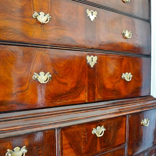 fig 4. A George I period figured walnut chest on stand featuring engraved brass escutcheons and six barley-twist legs.