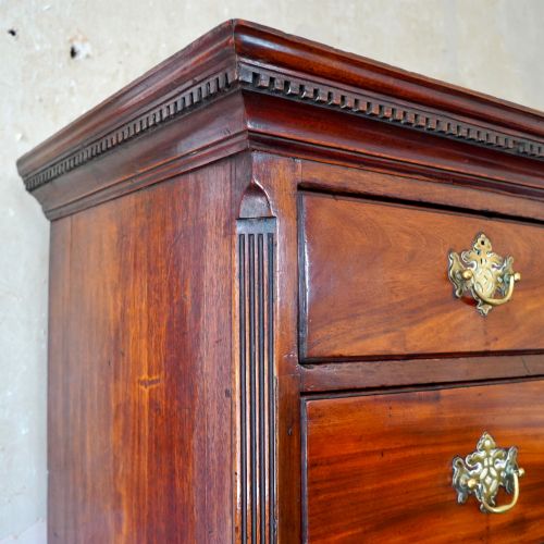 fig 4. A late 18th-century George III mahogany chest on chest featuring brass swan-neck handles, keyhole escutcheons, dentil moulding, and bracket feet.