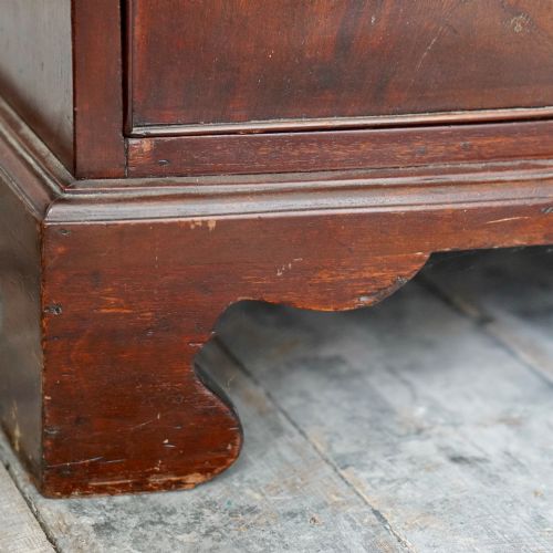 fig 4. A George III bowfront mahogany wardrobe featuring twin panelled doors with oval flame mahogany veneers above two drawers and flared bracket feet.