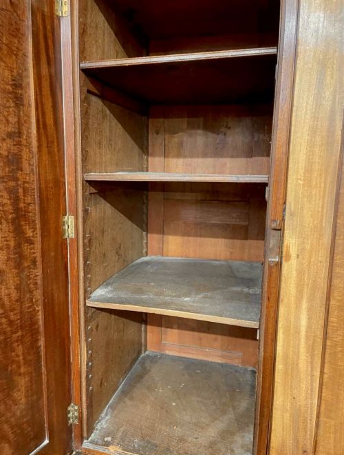 fig 5. A large George III mahogany breakfront linen press wardrobe featuring central panelled doors above drawers, flanked by side cupboards on bracket feet.
