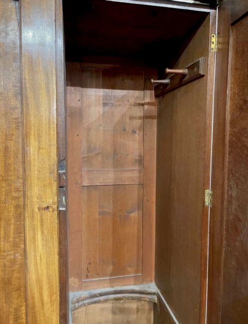 fig 6. A large George III mahogany breakfront linen press wardrobe featuring central panelled doors above drawers, flanked by side cupboards on bracket feet.