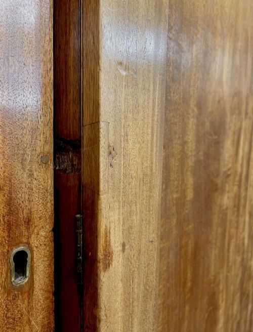 fig 7. A large George III mahogany breakfront linen press wardrobe featuring central panelled doors above drawers, flanked by side cupboards on bracket feet.