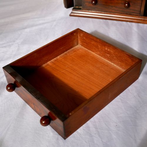 fig 2. A Regency period dark rosewood tabletop collectors cabinet featuring twin banks of small drawers flanking a central mirrored shelf unit with Gothic arched carving.