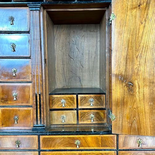 fig 2. An eighteenth-century early Georgian figured walnut escritoire featuring an open fall-front revealing a detailed fitted interior above a lower chest of drawers with brass handles.