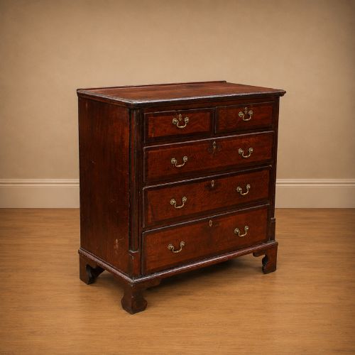 fig 1. A Georgian dark oak chest of drawers featuring two short drawers over three long drawers with mahogany crossbanding and brass swan-neck handles.