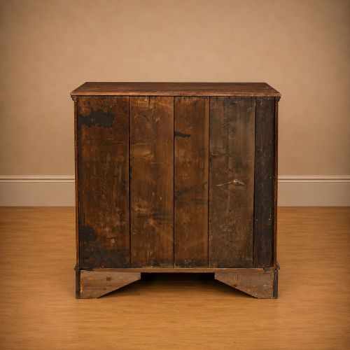 fig 4. A Georgian dark oak chest of drawers featuring two short drawers over three long drawers with mahogany crossbanding and brass swan-neck handles.