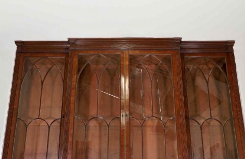 fig 7. A large George IV mahogany breakfront library bookcase featuring gothic astragal glazed upper doors above drawers and cupboard doors with geometric moulding.