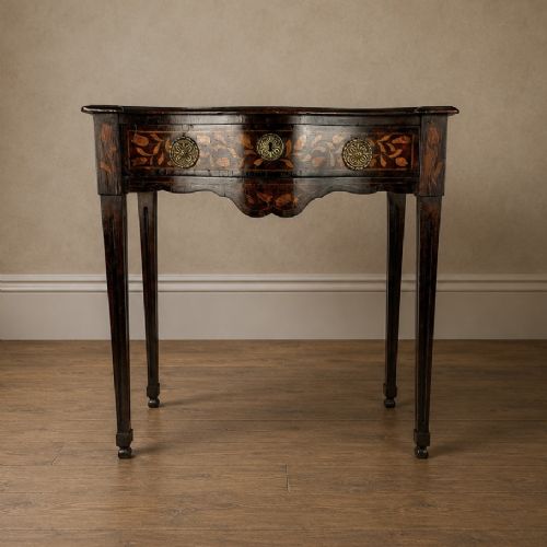 fig 1. An 18th-century Dutch walnut side table featuring a serpentine front, floral marquetry inlay, a single drawer, and four square tapered legs.