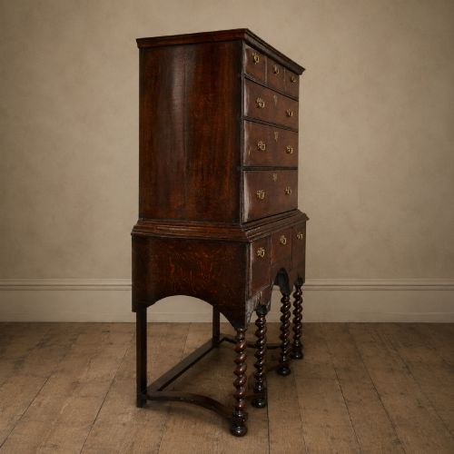 fig 3. A George I period figured walnut chest on stand featuring engraved brass escutcheons and six barley-twist legs.