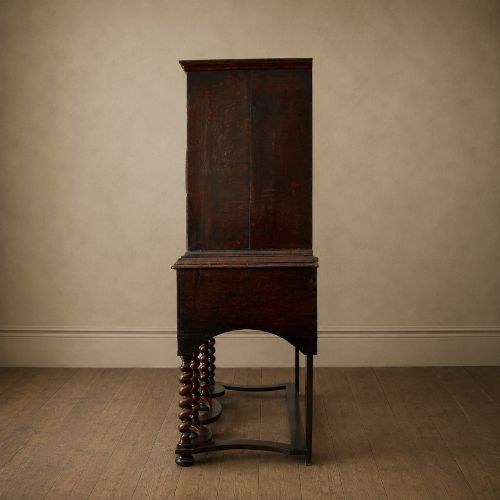 fig 4. A George I period figured walnut chest on stand featuring engraved brass escutcheons and six barley-twist legs.