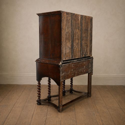 fig 6. A George I period figured walnut chest on stand featuring engraved brass escutcheons and six barley-twist legs.