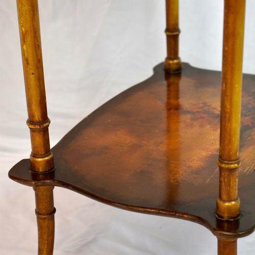 fig 7. A two-tier continental side table featuring hand-painted figural scenes on shaped wooden surfaces, supported by turned gilt legs.
