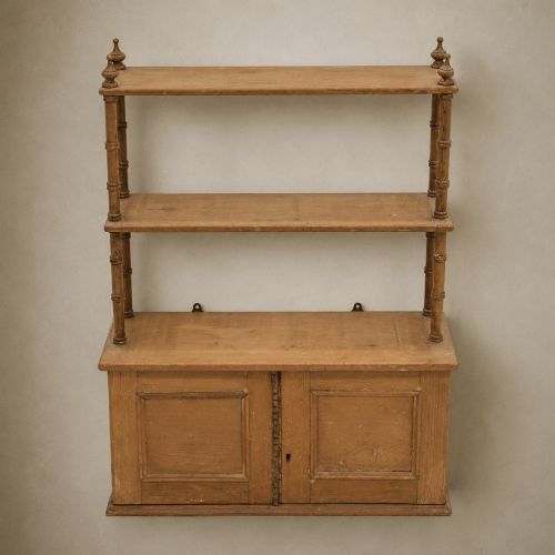 fig 2. A 19th-century wall-mounted pine rack featuring two open upper shelves supported by turned spindles with finials above an enclosed double-door cupboard.
