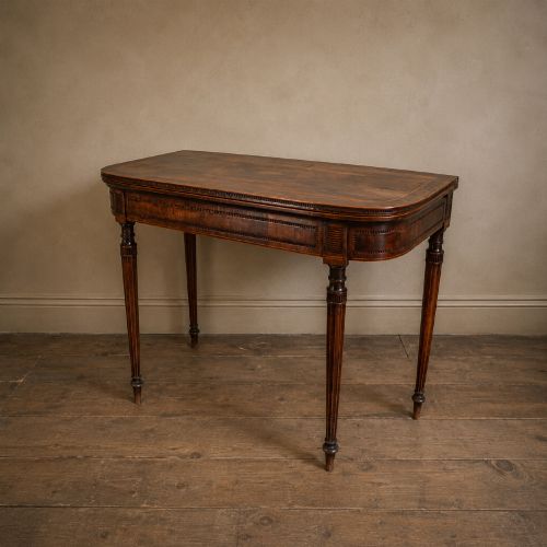 fig 5. An antique Regency rosewood fold-over card table featuring burr yew crossbanding, a rectangular top with rounded corners, and slender fluted tapered legs.