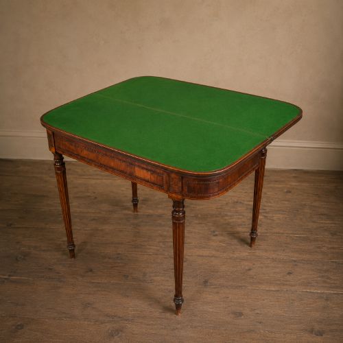 fig 7. An antique Regency rosewood fold-over card table featuring burr yew crossbanding, a rectangular top with rounded corners, and slender fluted tapered legs.