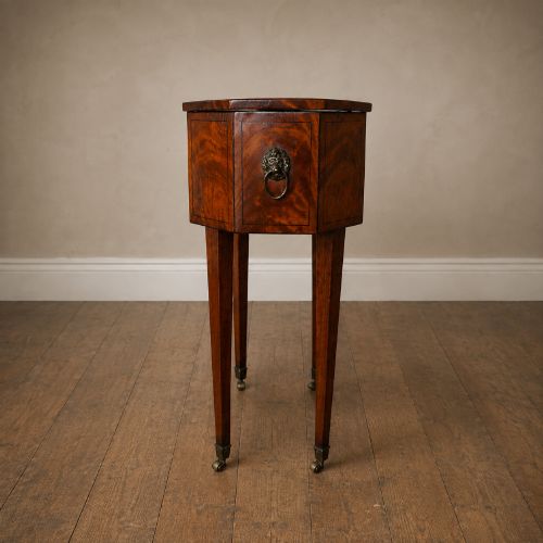 fig 6. An octagonal George III satinwood work table with two drawers, lion mask ring handles, and tapered legs ending in brass castors.