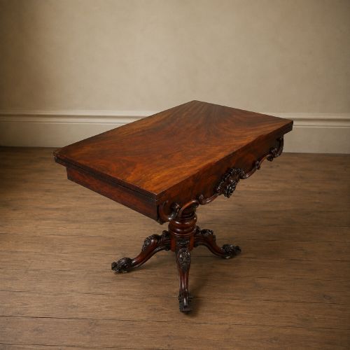 fig 8. A Victorian figured mahogany card table featuring a turnover top, carved frieze, turned pedestal, and scroll legs with castors.