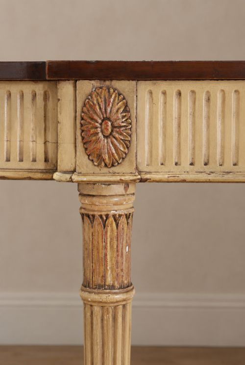 fig 4. A Georgian style painted cream and gilt console table featuring a dark wood top, fluted legs, and carved swag detailing.