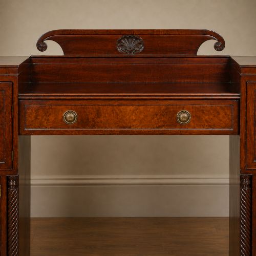 fig 5. A Regency figured mahogany pedestal sideboard with spiral-turned columns, brass drop handles, and a central carved splashback.