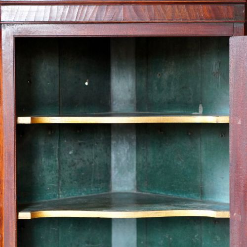 fig 7. A Georgian dark mahogany hanging corner cupboard featuring a swan-neck pediment with brass paterae and a single panelled door with a brass escutcheon.