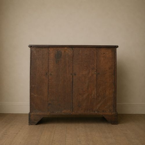fig 5. A George II dark mahogany straight-front chest featuring four graduated long drawers with decorative brass swan-neck handles and bracket feet.