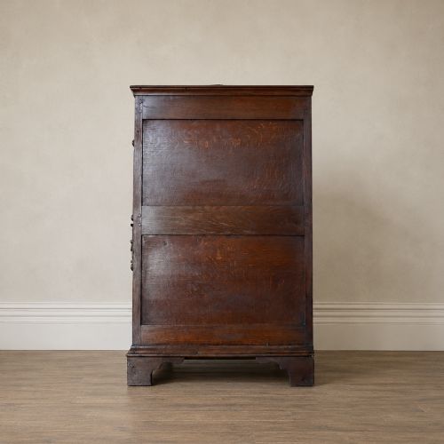 fig 2. An early eighteenth-century oak chest of drawers featuring four drawers decorated with geometric applied mouldings and brass drop handles.