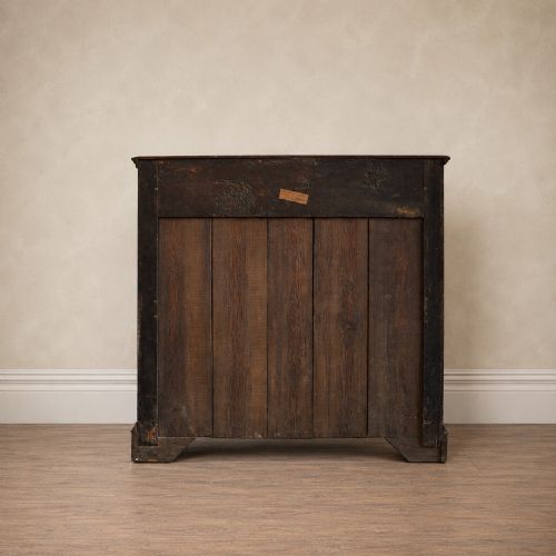 fig 3. An early eighteenth-century oak chest of drawers featuring four drawers decorated with geometric applied mouldings and brass drop handles.